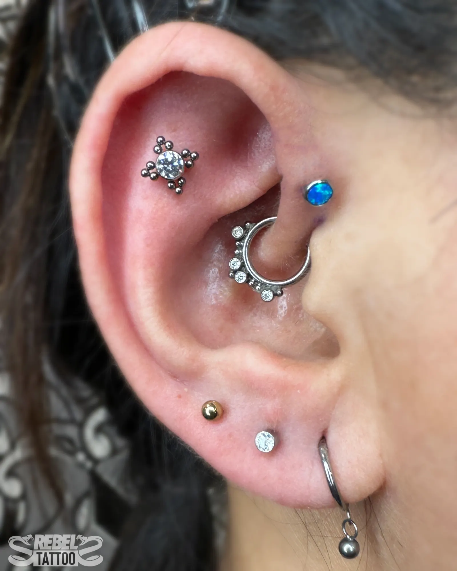 Layered ear curation with mixed stones in implant grade titanium, multi piercing at Rebel Tattoos Gurgaon