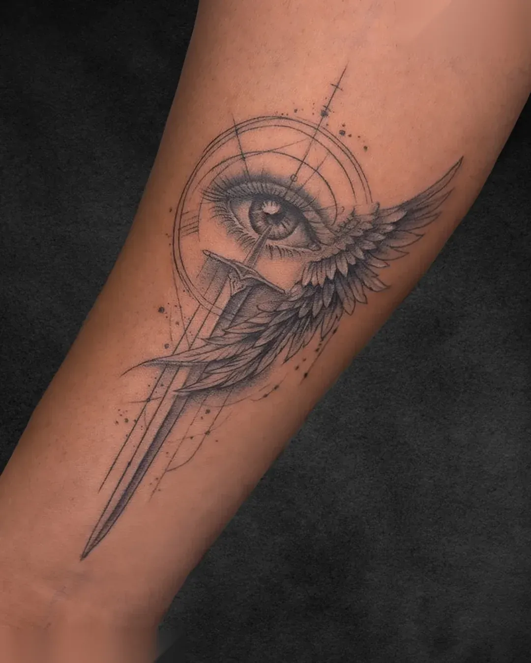 Eye and wing illustrative black and grey forearm tattoo at Rebel Tattoos Gurgaon